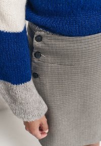 Sweter z mieszanki wełny w niebiesko-szary paski, połączony z spódnicą w wzór houndstooth z bocznymi guzikami, prezentującą teksturowany splot i dopasowany krój.