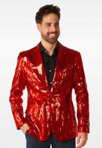 Roter Paillettenblazer mit rechtem Revers und einreihigem Knopfverschluss, darunter ein schwarzes Hemd und eine Tasche auf der linken Seite.