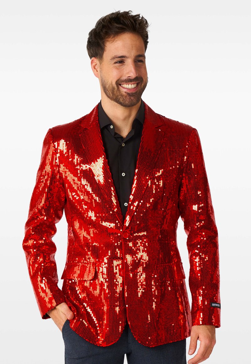 Roter Paillettenblazer mit rechtem Revers und einreihigem Knopfverschluss, darunter ein schwarzes Hemd und eine Tasche auf der linken Seite.