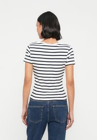 Ριγέ κοντομάνικο t-shirt σε λευκό και ναυτικό μπλε, με εφαρμοστή γραμμή και στρογγυλή λαιμόκοψη. Το ύφασμα φαίνεται μαλακό και ελαστικό.