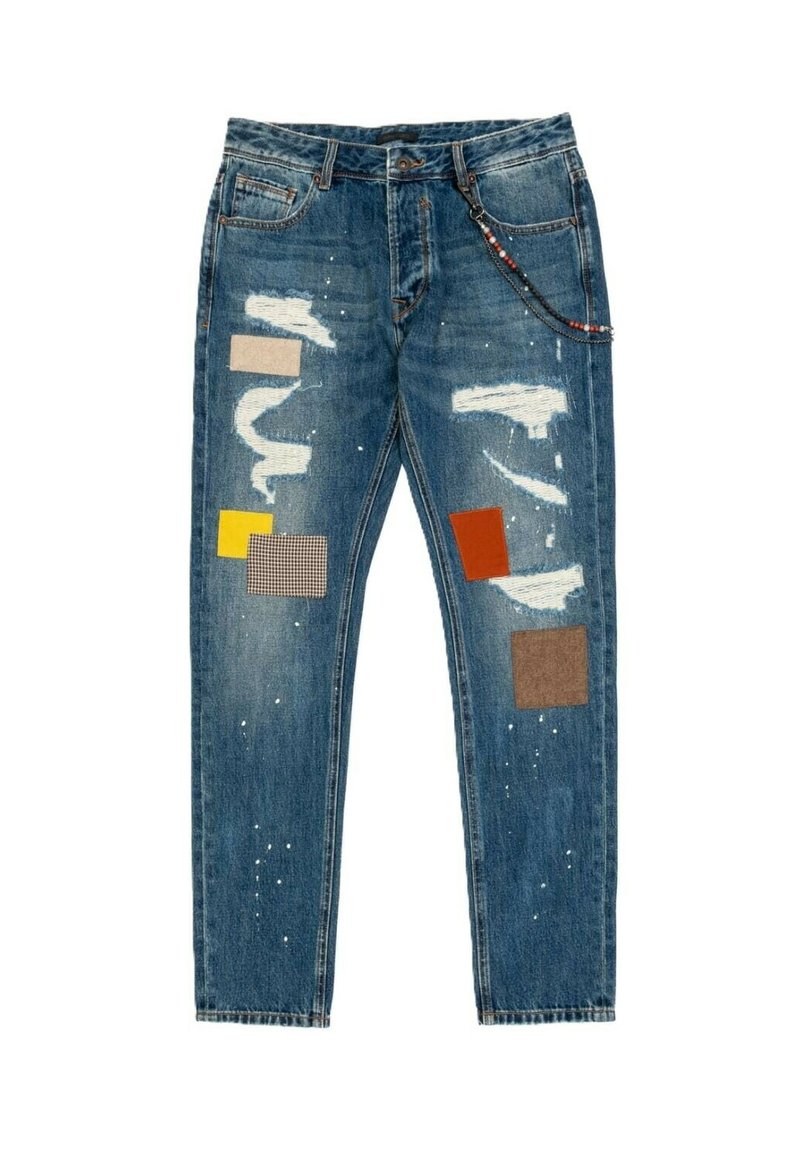 Vaqueros de mezclilla azul con corte slim, que presentan parches desgastados, acentos de tela multicolor y sutiles manchas de pintura en las piernas.