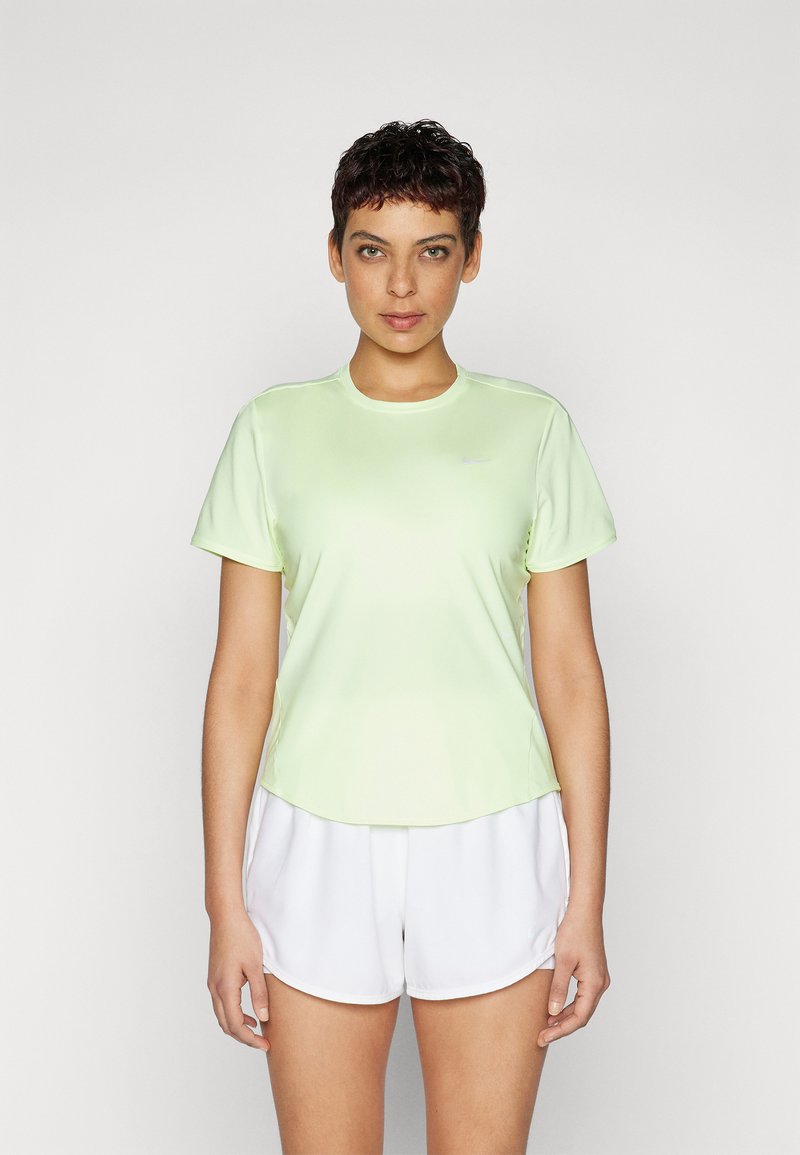 Camiseta atlética verde claro de manga corta y escote redondeado, combinada con pantalones cortos blancos. El tejido parece suave y ligero.