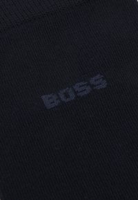 Marina strumpor tillverkade av ett mjukt, strukturerat tyg med en subtil "BOSS"-logotyp i en något ljusare nyans vävd i materialet.