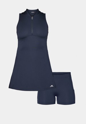 Tumesinine sportlik kleit, millel on tõmblukuga kaelus, vormitud kehajaotus ja laiendav seelik, koos sobivate lühikeste pükste ja. Sile tekstuur, minimaalne bränding.