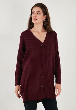 Burgundy ribbed cardigan featuring a deep V-neck, long sleeves, and six large buttons down the front. Soft knit texture with a loose fit.