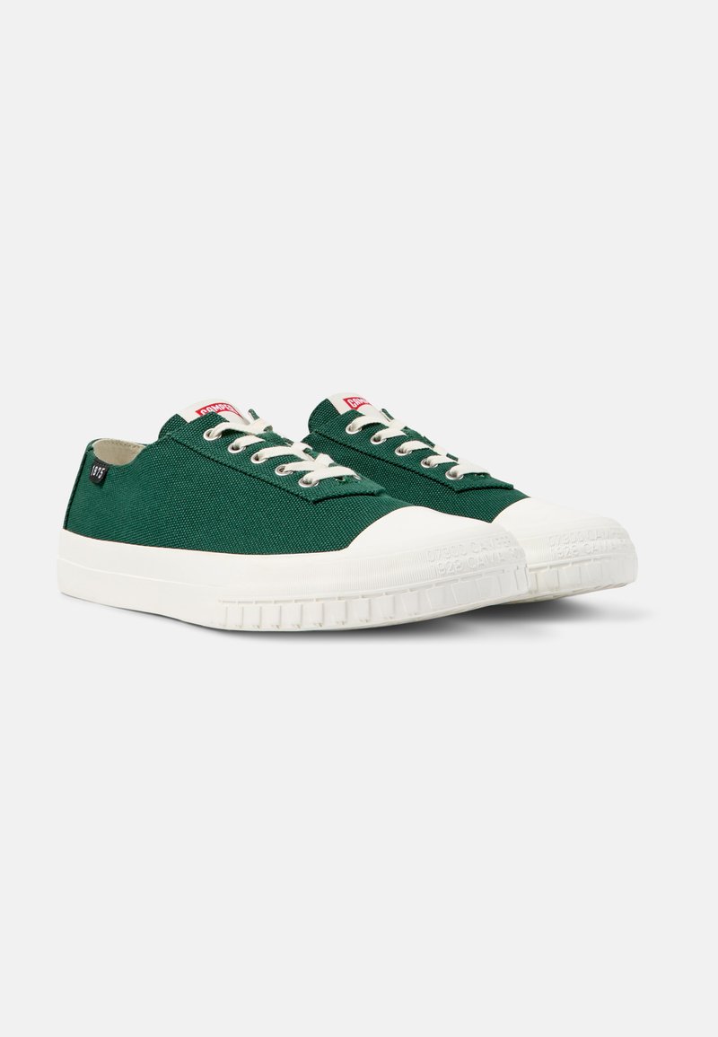 Sneakers in tela verde con punta e suola in gomma bianca, dotati di lacci bianchi e di un'etichetta logo rossa sul lato. Design piatto, stile casual.