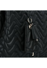 Zwarte, gewatteerde leren tas met golvende textuur, voorzien van een sleutelhanger en metalen accenten. Compact ontwerp met een strakke, moderne esthetiek.