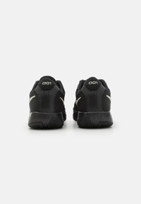 Svarte treningssko med mesh-overdel, teksturert detalj og hæltab med tallet "001." Inkluderer ventilasjonsåpninger på sidene.