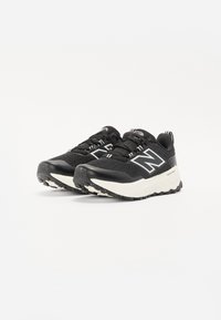Chaussures de sport noires avec tige en mesh, embout renforcé, accents blancs et semelle en caoutchouc texturé conçue pour l'adhérence et le confort.