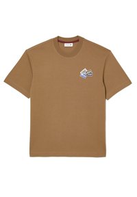 Camiseta corta de manga con cuello redondo en color marrón, con un pequeño parche multicolor en el lado izquierdo del pecho que muestra diversas palabras relacionadas con el deporte.