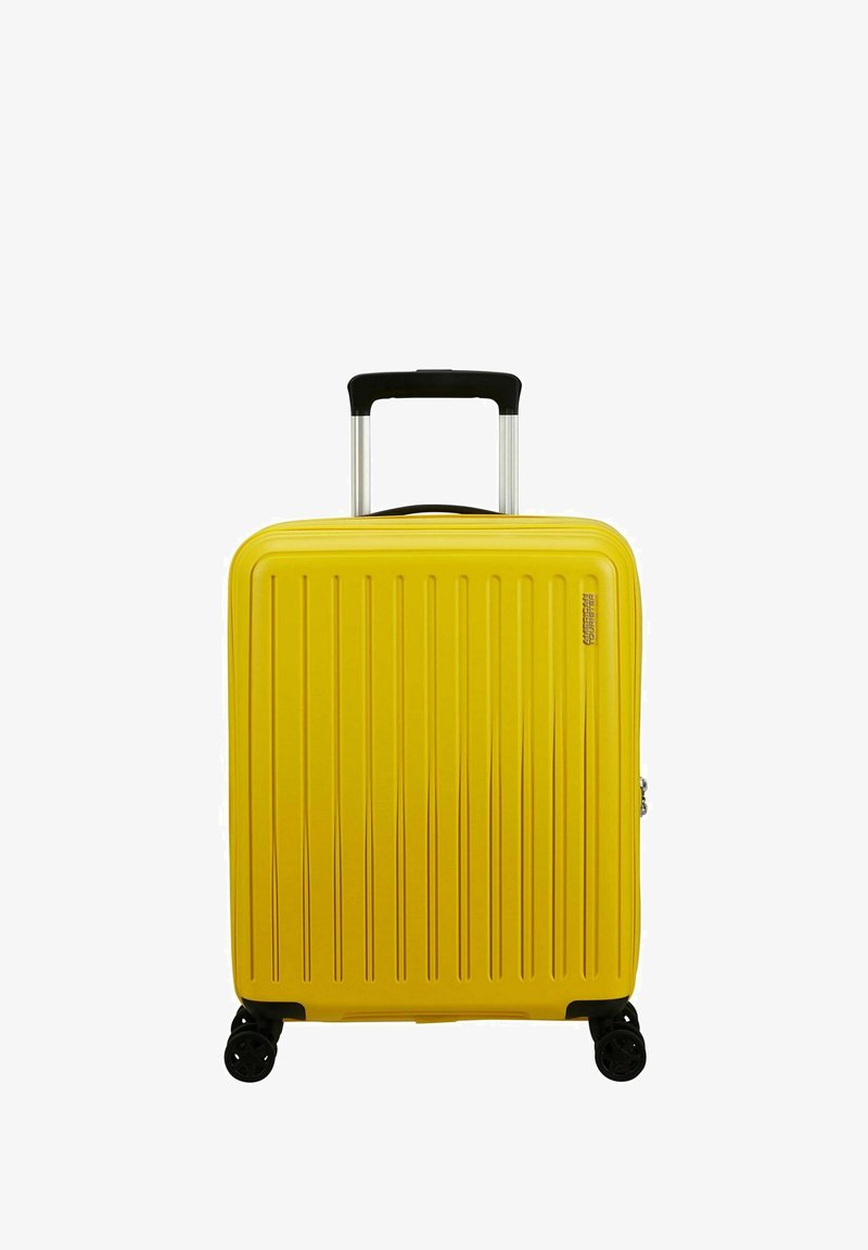 Valise jaune en plastique rigide avec un design à rainures verticales, poignée rétractable et quatre roues noires pour la mobilité. Fermeture éclair sur le côté.