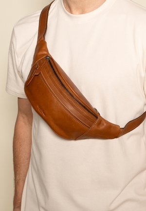 Riñonera de cuero marrón con forma curva, que cuenta con un compartimento con cremallera, costuras en contraste y una correa ajustable.