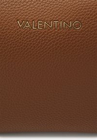 Hnědá kožená peněženka s texturovaným povrchem. Ražené logo "VALENTINO" ve zlaté barvě, umístěné uprostřed nahoře. Jednoduchý a obdélníkový design.