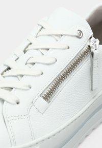 Λευκό δερμάτινο αθλητικό παπούτσι με υφή, επίπεδα κορδόνια και πλευρικό φερμουάρ με ασημένια μεταλλικά στοιχεία. Λείο καουτσούκ πάτο σε αντιστοιχισμένο χρώμα.
