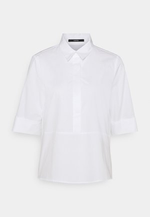 Camicia bianca a maniche corte con colletto, chiusura frontale a bottoni e design senza cuciture. Tessuto liscio dallo stile semplice e minimalista.