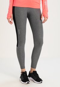 Grå träningsbyxor med svarta sidpaneler, som har en slät yta och en åtsittande design. Logotyper tryckta på tyget.