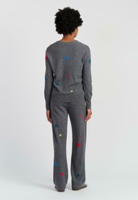 Grijze gebreide trui en broekset met meerkleurige sterrenpatronen; zachte textuur, ronde hals, aansluitende manchetten en een ontspannen pasvorm.