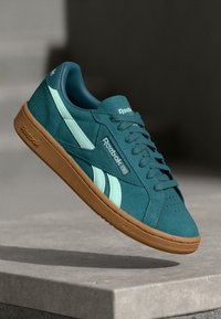 Türkise Wildleder-Sneaker mit hellblauen Akzenten, ausgestattet mit einer strukturierten Gummisohle und Reebok-Branding auf der Zunge und der Seite.