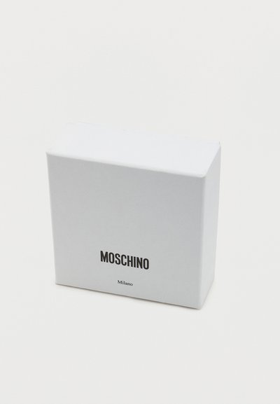 Λευκό ορθογώνιο κουτί με μαύρο κείμενο "MOSCHINO" και μικρότερο "Milano" μπροστά, τοποθετημένο σε λευκό απλό φόντο.