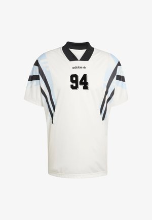 Biały sportowy trykot z krótkimi rękawami, czarnym kołnierzem oraz niebiesko-czarnymi skośnymi paskami. Numer „94” wyraźnie widoczny na czarno.