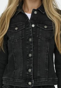 Svart denimjacka med figursydd design, silverfärgade knappar, dubbla bröstfickor och subtil blekning, med sydda detaljer längs sömmarna.