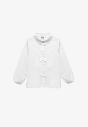 White long-sleeve shirt with a round collar, front button closure, lace detailing, and two small bows at the center. Smooth fabric texture.