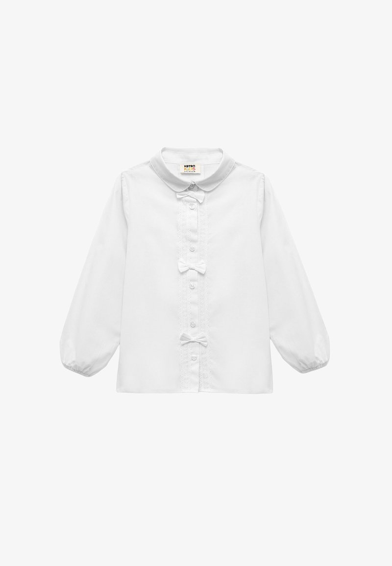 Hvid langærmet skjorte med rund krave, frontknaplukning, blonde detaljer og to små sløjfer i midten. Glat stofstruktur.