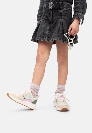 Baskets claires avec une combinaison de rose pastel, vert et beige, comportant des accents en mesh et des semelles texturées. Portées avec des chaussettes grises.