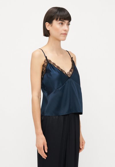 Zīda kamoliens tumši zilā krāsā ar melnu mežģīņu apdari ap dekoltē un regulējamām spageti siksnām. Plūstoša, nedaudz brīva piegriezuma.