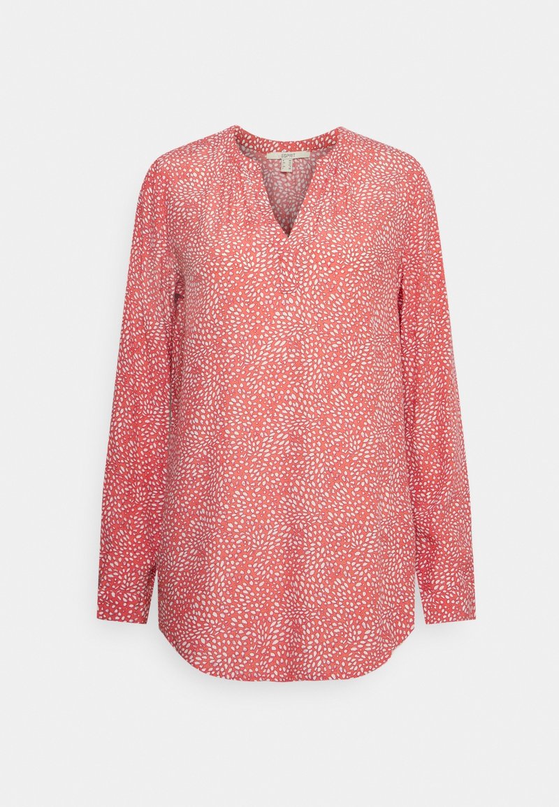 Blouse manches longues rose corail avec motif de points blancs irréguliers, encolure en V et ourlet arrondi.