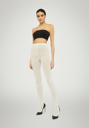 Collant bianchi opachi con una texture liscia, vita alta e design senza cuciture, abbinati a tacchi a stiletto neri e un top bandeau nero.