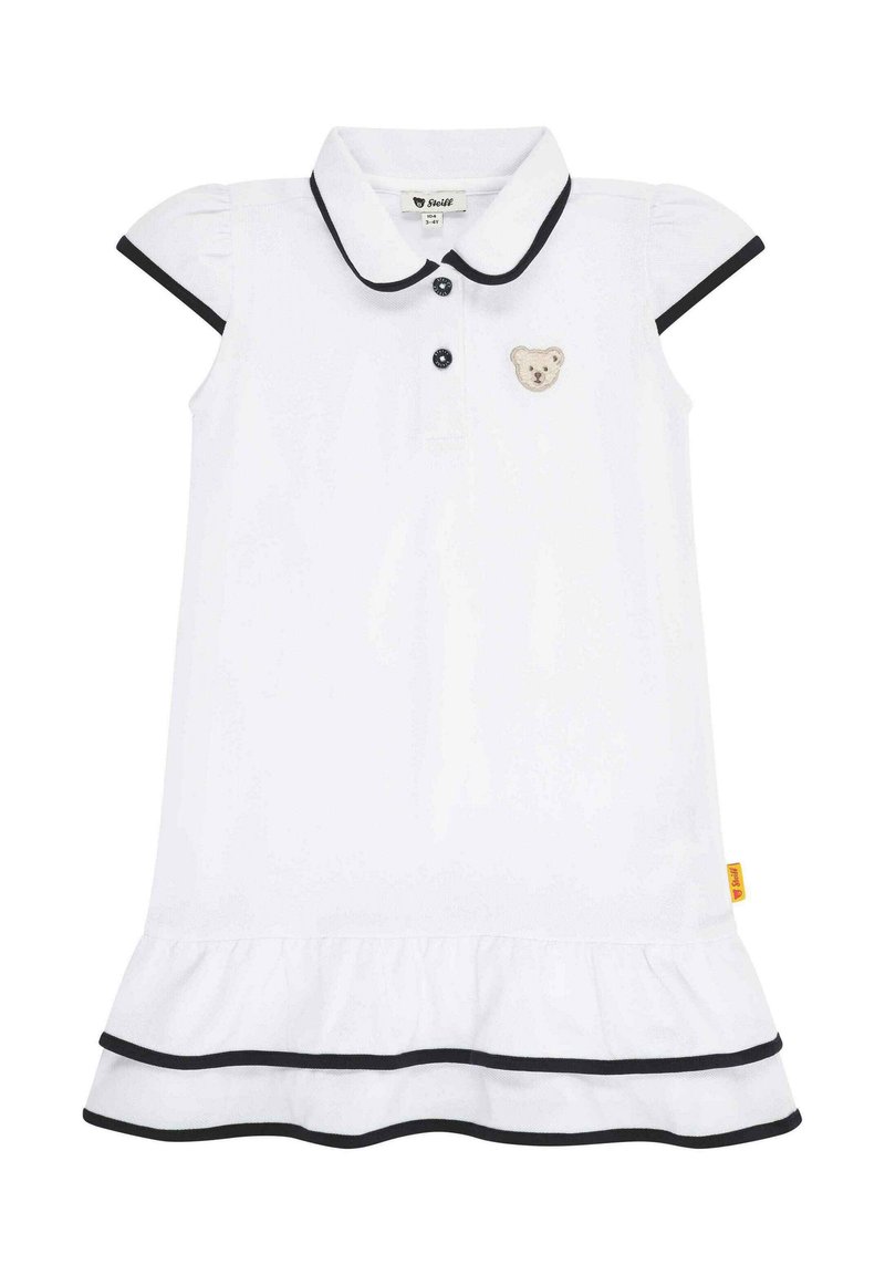 Witte polojurk met korte pofmouwen, zwarte afwerking, een knoopsluiting en een geborduurd berenpatch op de borst. Rimpelzoom.