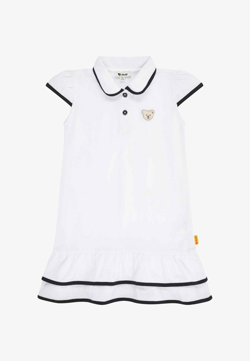 Weißes Polo-Kleid mit kurzen Puffärmeln, schwarzem Besatz, Druckknopfverschluss und einem gestickten Bären-Patch auf der Brust. Rüschensaum.
