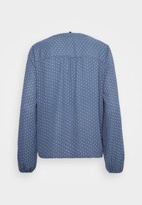 Blusa azul de mangas compridas com bolinhas brancas, apresentando um decote redondo, detalhes franzidos nas costas e punhos elásticos. Tecido de textura suave.