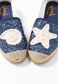 Espadrilles bleu marine avec tige scintillante, dotées d'une coquille crème et d'une étoile en décoration, avec une semelle en corde de jute.