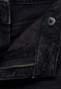 Črn denimski material z gladko teksturo in prešito podlogo. Vključuje gumb za zapiranje in žep z zadrgo za varno shranjevanje.