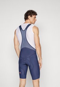 Navy lycra-bib-shorts valmistettu joustavasta kankaasta, jossa on verkkoolkaimet ja pehmustettu takapuoli. Ominaisuuksiin kuuluvat kontrastivärinen ommeltu ja logo-patch sääressä.