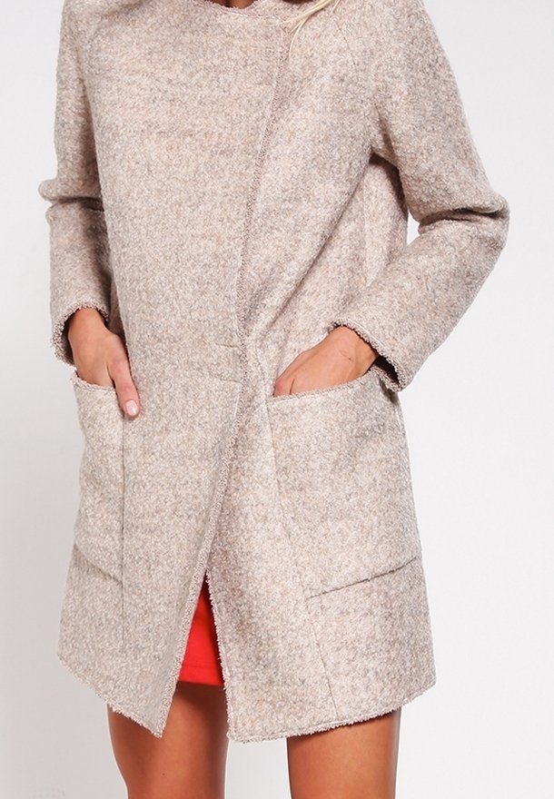 Cappotto in lana beige chiaro con vestibilità rilassata, maniche lunghe e due tasche anteriori. Presenta una texture morbida e dettagli di cucitura minima.