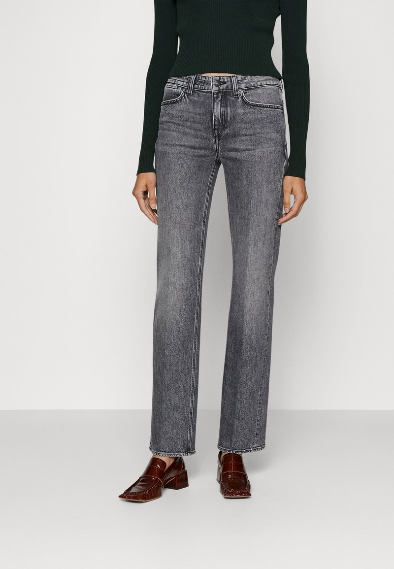 Jeans grises de cintura alta con un diseño de pierna recta, que presentan un desvanecimiento sutil y un estilo de cinco bolsillos, combinados con mocasines marrón oscuro.