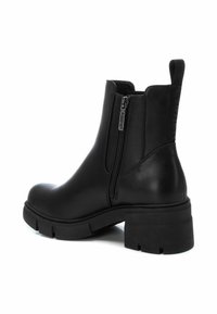 Botas de cuero negras hasta el tobillo con un tacón grueso, cremallera lateral y acentos texturizados. Acabado suave y diseño de suela de goma resistente.