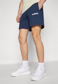 Marinblå shorts med Hummel-logga, tillverkade av mjukt tyg, med regular fit, elastisk midja och sidofickor.