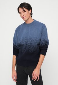 Sweater em degradê azul com decote redondo, apresentando um design texturizado que transita do azul claro para o azul marinho escuro na barra e nas mangas.