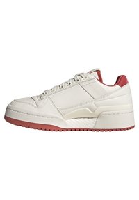 Vita lädersneaker med en texturerad yta, röda hälsidor, och en upphöjd sula. Har sex snörningshål och perforerade detaljer vid tårna.