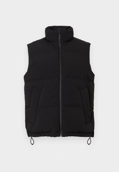 Zwarte gewatteerde vest met hoge kraag, ritssluiting aan de voorkant en twee voorzakken. Heeft een strakke onderkant en een gladde, matte textuur.