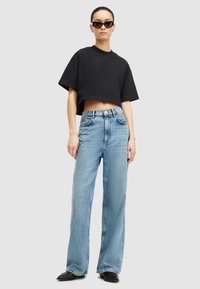 Melnā īsā krekla ar īsām piedurknēm kombinācija ar gaiši ziliem platiem džinsiem. Džinsiem ir augsts jostasvietas līmenis un klasiskā piecu kabatu dizains.