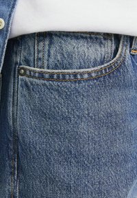 Blaue Jeans aus Denim mit einem klassischen Fünf-Taschen-Design, sichtbarer Naht und einem strukturierten Stoff mit leichtem Used-Look.