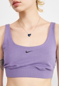 Purple cotton sports bra with a scoop neckline, black Nike logo on the front, and a fitted design. Accented with smooth fabric texture.