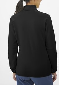 Black, long-sleeve jacket with a high collar and smooth texture. Features raglan sleeves and a fitted silhouette, shown from the back.