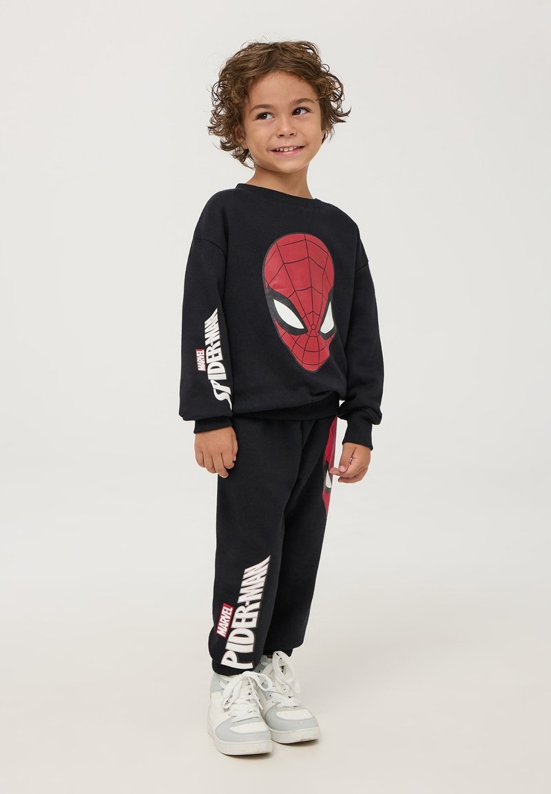 Felpa nera e pantaloni della tuta con una grande grafica di Spider-Man; testo rosso e bianco sui pantaloni; tessuto morbido; vestibilità rilassata.