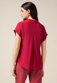 Rood short-sleeve shirt met een zachte textuur, met een rugplooi en ronde zoom. Lichte stof, casual ontwerp, aangevuld met roze broek.